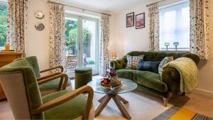 ein Wohnzimmer mit einem grünen Sofa und zwei Stühlen in der Unterkunft Wildflowers Cottage in Bourton on the Water + 16 Fotos