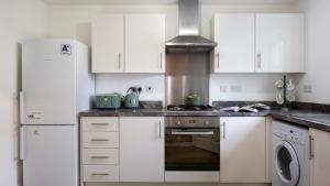 eine Küche mit weißen Schränken und einem Herd mit Backofen in der Unterkunft Wildflowers Cottage in Bourton on the Water