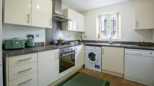 eine Küche mit weißen Schränken und einer Waschmaschine und einem Trockner in der Unterkunft Wildflowers Cottage in Bourton on the Water