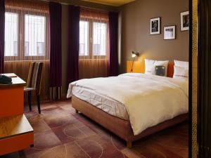 a bedroom with a bed and a desk and windows at 25hours Hotel The Trip in Frankfurt/Main