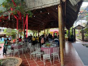 a group of people sitting at tables in a pavilion at Homestay Cô Hai in Xóm Rạch Già