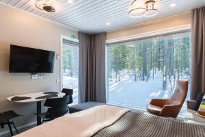 ein Schlafzimmer mit einem Bett und einem großen Fenster mit einem Tisch und Stühlen in der Unterkunft Halla Chalet, Northern Lights, ski & lake, free wifi, Vuosseli Resort Ruka in Kuusamo