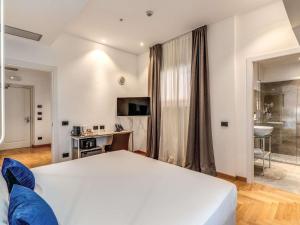 a bedroom with a large white bed and a bathroom at Mercure Roma Centro Termini in Rome