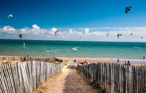 a group of people flying kites on the beach at Maison Près De La Mer in LʼAiguillon-sur-Mer +20 photos