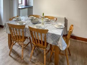 une table à manger avec des chaises et un tissu de table dans l'établissement Mistletoe Cottage - Uk50581, à Brean