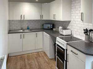 une cuisine avec des armoires blanches et un four à plaques de cuisson dans l'établissement Mistletoe Cottage - Uk50581, à Brean