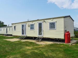 a mobile home with a red fire hydrant in front of it at Praise Machine Caravan Experience in Jaywick Sands