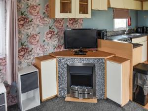 a kitchen with a fireplace with a tv on it at Praise Machine Caravan Experience in Jaywick Sands