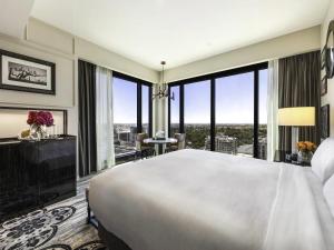 アデレードにあるSofitel Adelaideの大きな窓のある部屋にある大きな白いベッド