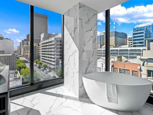 a bathroom with a tub and a view of a city at Sofitel Adelaide in Adelaide