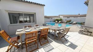 a patio with a table and chairs and a pool at Belle maison familiale avec piscine et parking in Loix