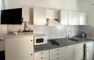 a kitchen with white cabinets and a sink and a microwave at Awesome Apartment In Duce With House Sea View in Duće
