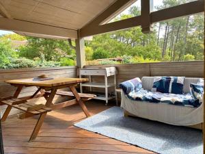 porche con sofá y mesa en la cubierta en Kôté Sea Apartment, en Seignosse