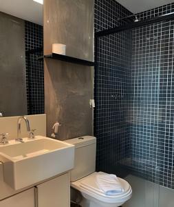 a bathroom with a white toilet and a sink at Geo Berrini Residences in Sao Paulo