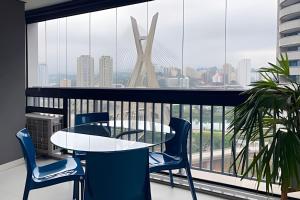a balcony with a table and chairs and a large window at Geo Berrini Residences in Sao Paulo