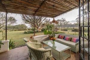 a patio with a couch and chairs and a table at Sanctuary Farm House 5-bedroom Lodge In Wildlife in Naivasha +13 photos