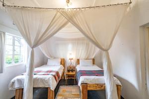 a bedroom with two beds and a canopy at Sanctuary Farm House 5-bedroom Lodge In Wildlife in Naivasha