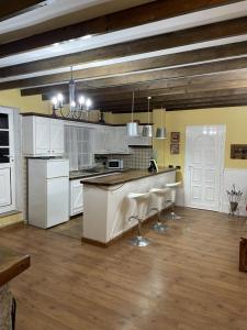 een keuken met witte kasten en een bar met krukken bij La Era in La Concepción