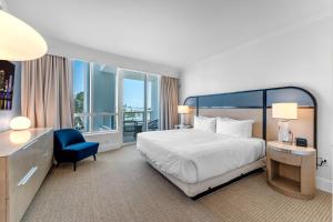 a hotel room with a bed and a blue chair at Fontaine Bleau Suite - Street & Partial Ocean view in Miami Beach +32 photos