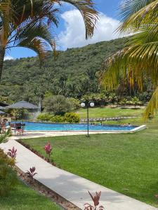a resort swimming pool with palm trees and a mountain at Águas da Serra Condomínio in Bananeiras