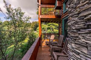 a wooden deck with two chairs and a balcony at Windswept Vistas in Boone