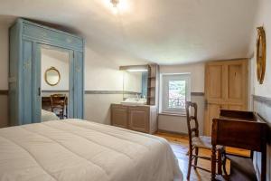 ein Schlafzimmer mit einem Bett, einem Schreibtisch und einem Waschbecken in der Unterkunft La maison du château in Fontaine-de-Vaucluse