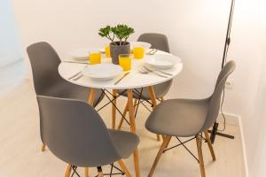 a white dining room table with chairs and orange juice at Canasteros Apartments ! in Málaga +23 photos