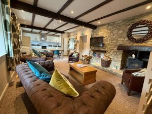 a living room with a leather couch and a fireplace at Tuckers Grave Inn - Historic Inn & Cider Pub in Norton Saint Philip