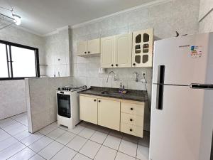 Una cocina con electrodomésticos blancos y un refrigerador blanco. en A 3 min do Mar e 5 da Feirinha - Guilhermina!, en Praia Grande