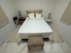 een witte slaapkamer met een bed en een stoel bij COMPLEJO JONAS SALK - departamento de 1 dormitorio amoblado in San Francisco