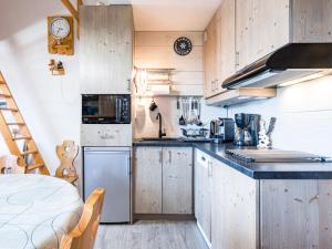 eine Küche mit Holzschränken und einer Arbeitsplatte in der Unterkunft Grand Horizon 1 N403 2P8 in Morillon + 5 Fotos