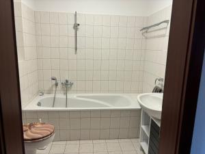 a bathroom with a tub and a toilet and a sink at Gemütliche 2-Zimmerwohnung in Schönefeld
