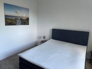 a bedroom with a white bed with a picture on the wall at Gemütliche 2-Zimmerwohnung in Schönefeld