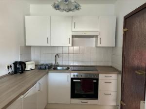 a kitchen with white cabinets and a stove top oven at Gemütliche 2-Zimmerwohnung in Schönefeld +4 photos