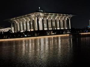 a large building at night with a body of water at Homestay Putrajaya Ayer 8 Elzahra Suites With Wi Fi in Putrajaya