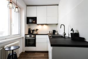 a kitchen with white cabinets and a black counter top at apartmán NA NOC V BOHDANČI in Lázně Bohdaneč