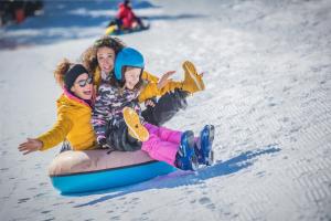 two girls are riding on a sled in the snow at Residence Abete in Marilleva +9 photos