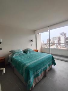 a bedroom with a bed and a large window at Edificio Matiz Cavancha in Iquique