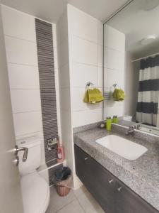 a bathroom with a sink and a toilet and a mirror at Edificio Matiz Cavancha in Iquique