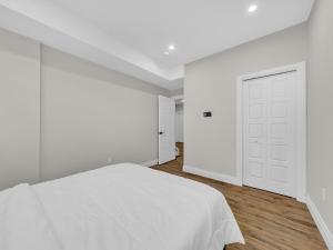 a white bedroom with a white bed and wooden floors at Windsor Perfect Stay in Windsor