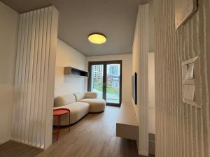 a living room with a white couch and a tv at Metropolis- brand new apartment with free parking in Nivy