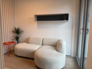 a living room with a white couch and a tv at Metropolis- brand new apartment with free parking in Nivy