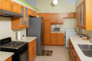 Una cocina con gabinetes de madera y un refrigerador de acero inoxidable. en Luxury Tropical Escape Pool & Gym Sleeps 7, en Richmond