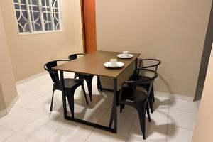 a wooden table with black chairs and a cup on it at Apê espaçoso e tranquilo pertinho do centro! in Barreiras +1 photo