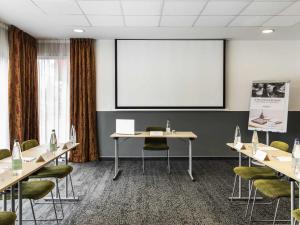 a meeting room with tables and chairs and a screen at Mercure Belfort Centre in Belfort