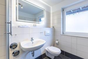 a white bathroom with a sink and a toilet at Boddenräuber 3 in Ahrenshoop +14 photos