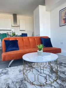 an orange couch with blue pillows and a table at The Felix Apartments - 1 Bedroom - WIFI - FREE Parking in Flitwick