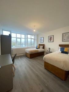 a room with two beds and a desk and windows at The Felix Apartments - 2 Bedrooms - WIFI - FREE Parking in Flitwick