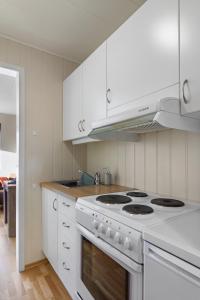a kitchen with white cabinets and a stove top oven at Fjellheim Kurs- og Misjonssenter in Tromsø +6 photos