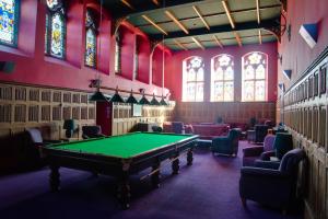 a pool table in a room with chairs and stained glass windows at Abbey Church 20 in Fort Augustus